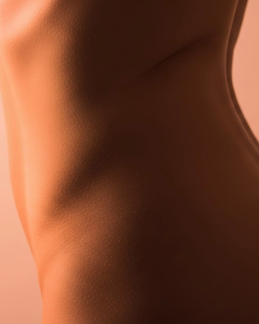 A bare back and shoulder turned away from the light.