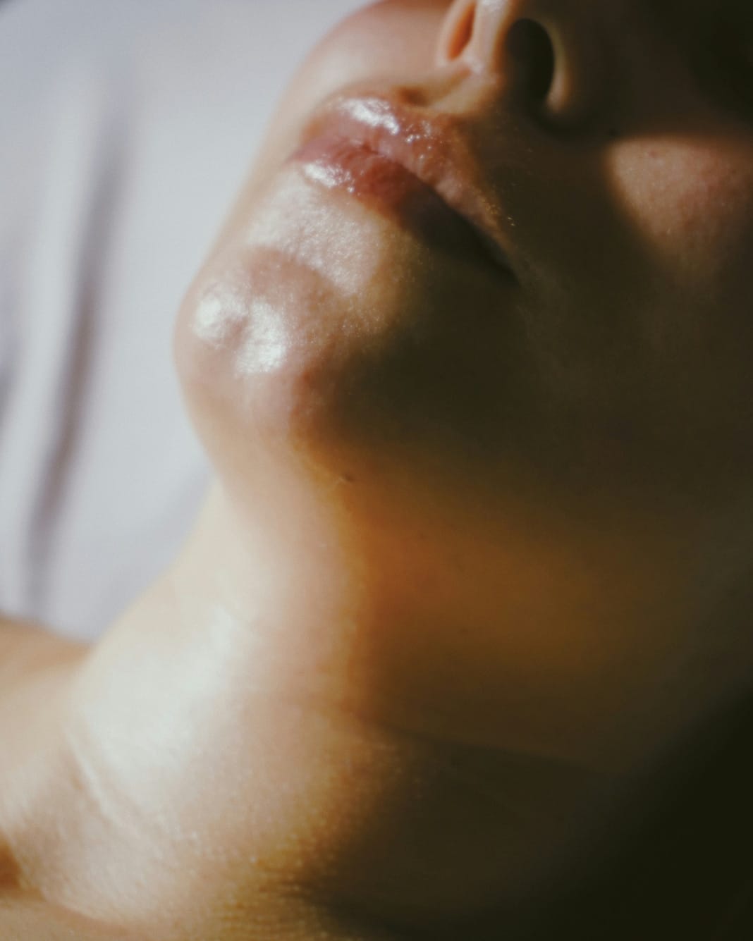 A face tilted back toward the light, eyes closed.