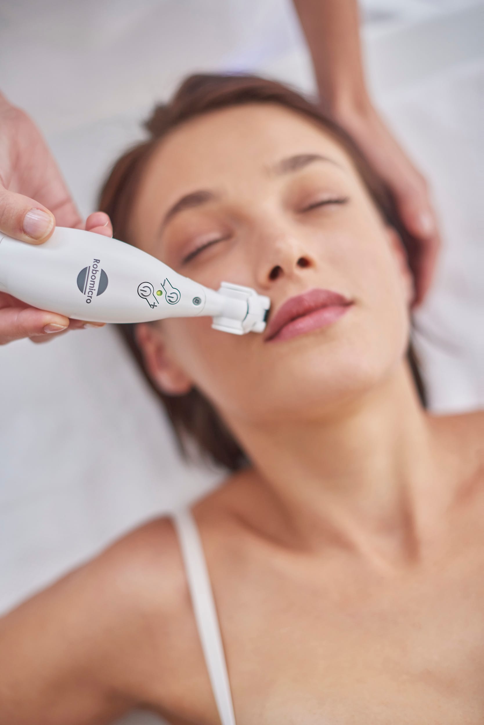 An ICOONE handpiece guided along a client&rsquo;s cheek during a facial treatment.